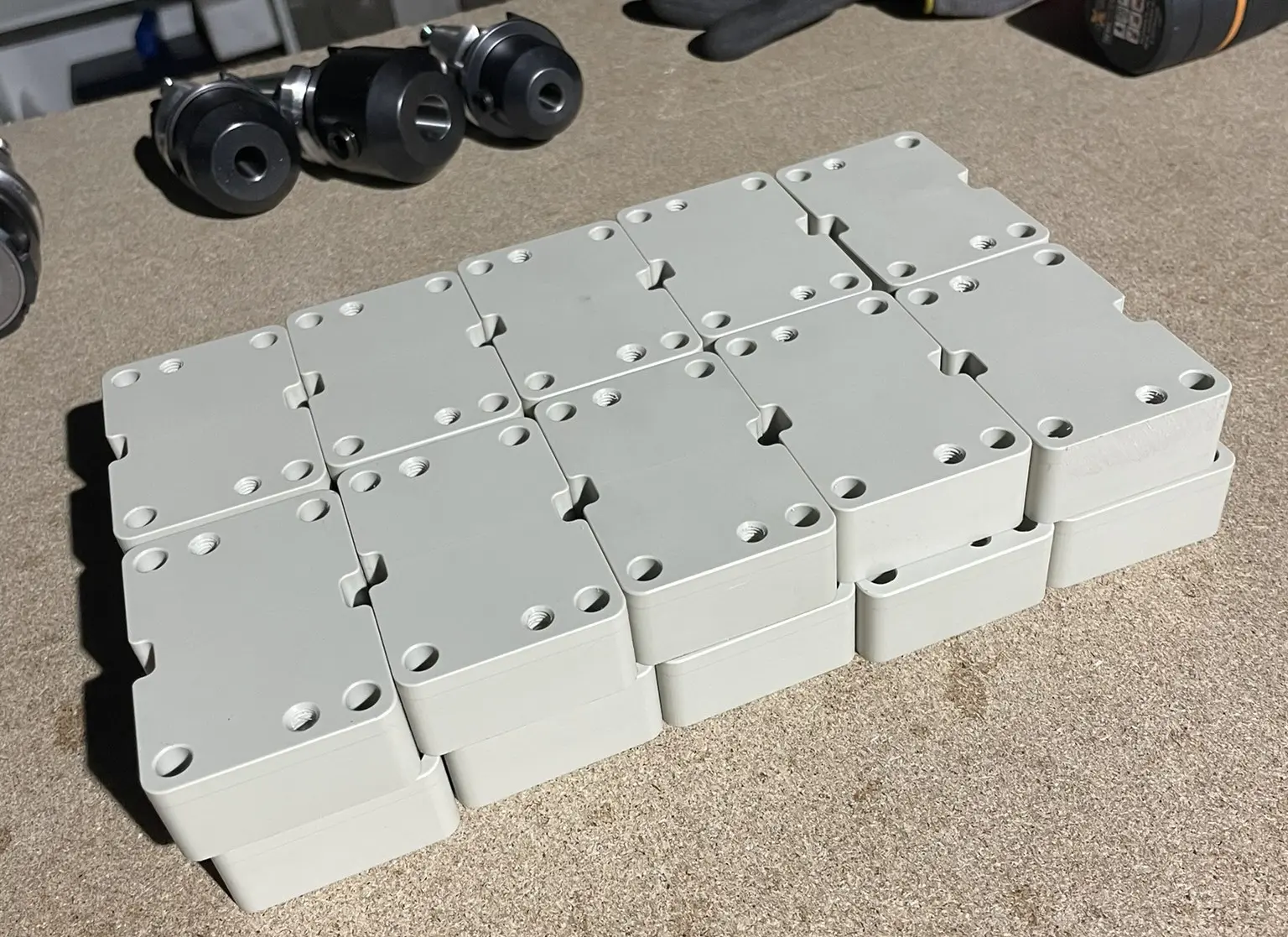 Plastic machined parts on a MDF work surface with tools and work gloves in the background.