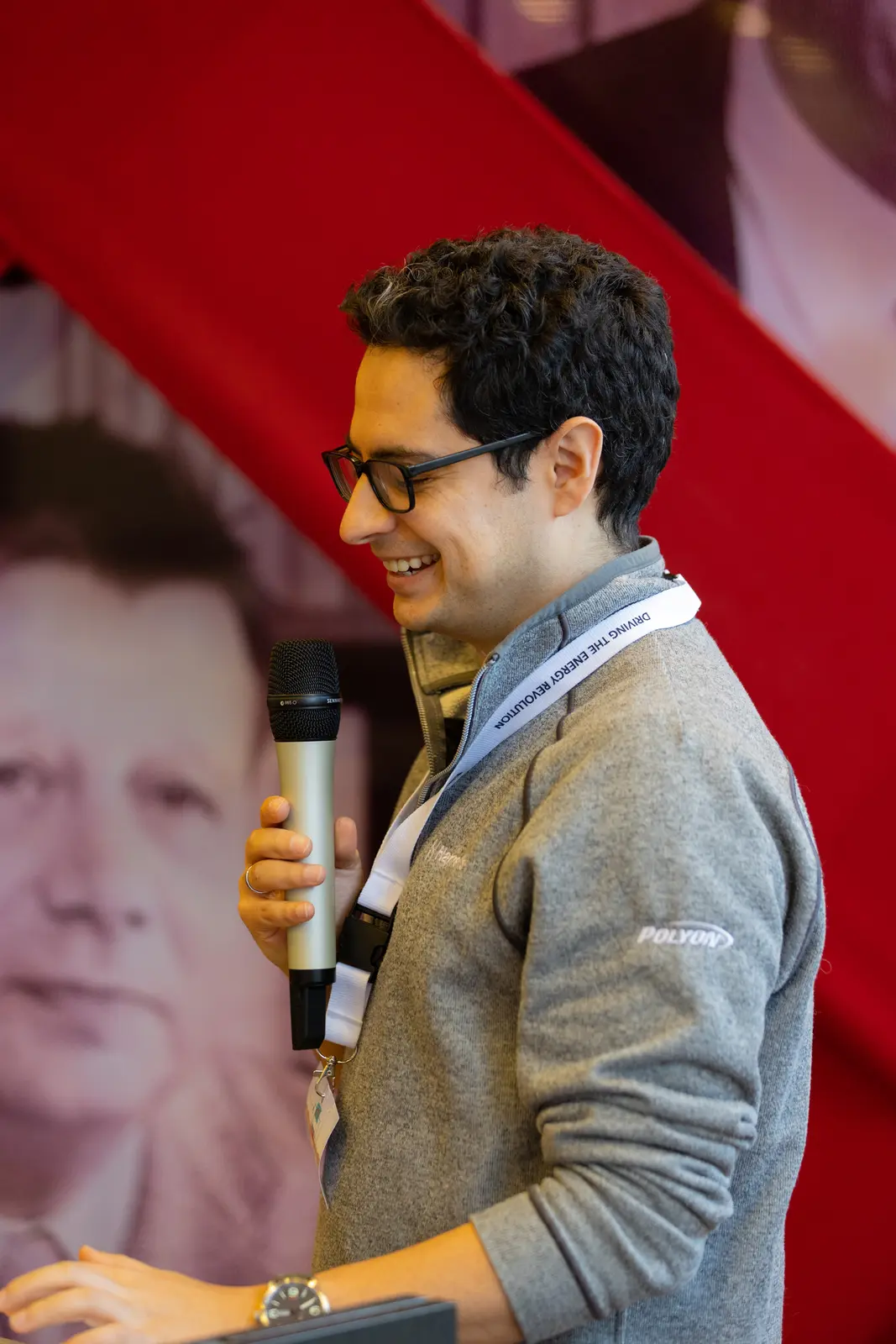 A man addressing an audience from a podium while holding a microphone